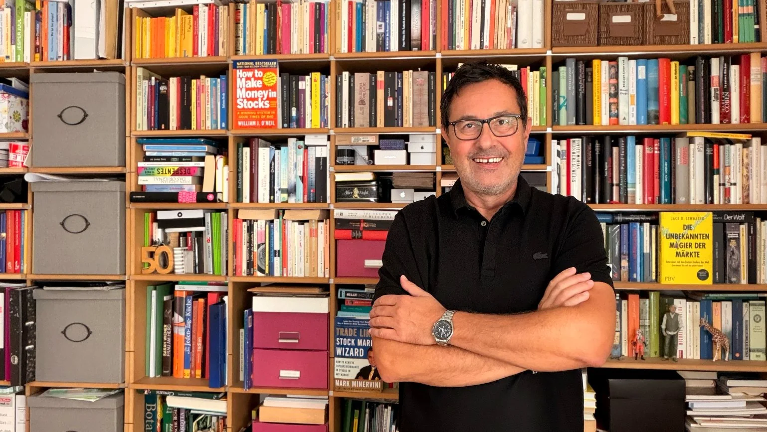 Dirk Siebenhaar mit verschränkten Armen vor seiner Bücherwand